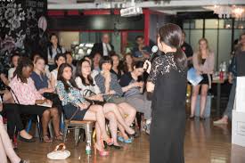 A speaker addresses an attentive audience in a stylish venue, showcasing a diverse group of women engaged in a discussion.