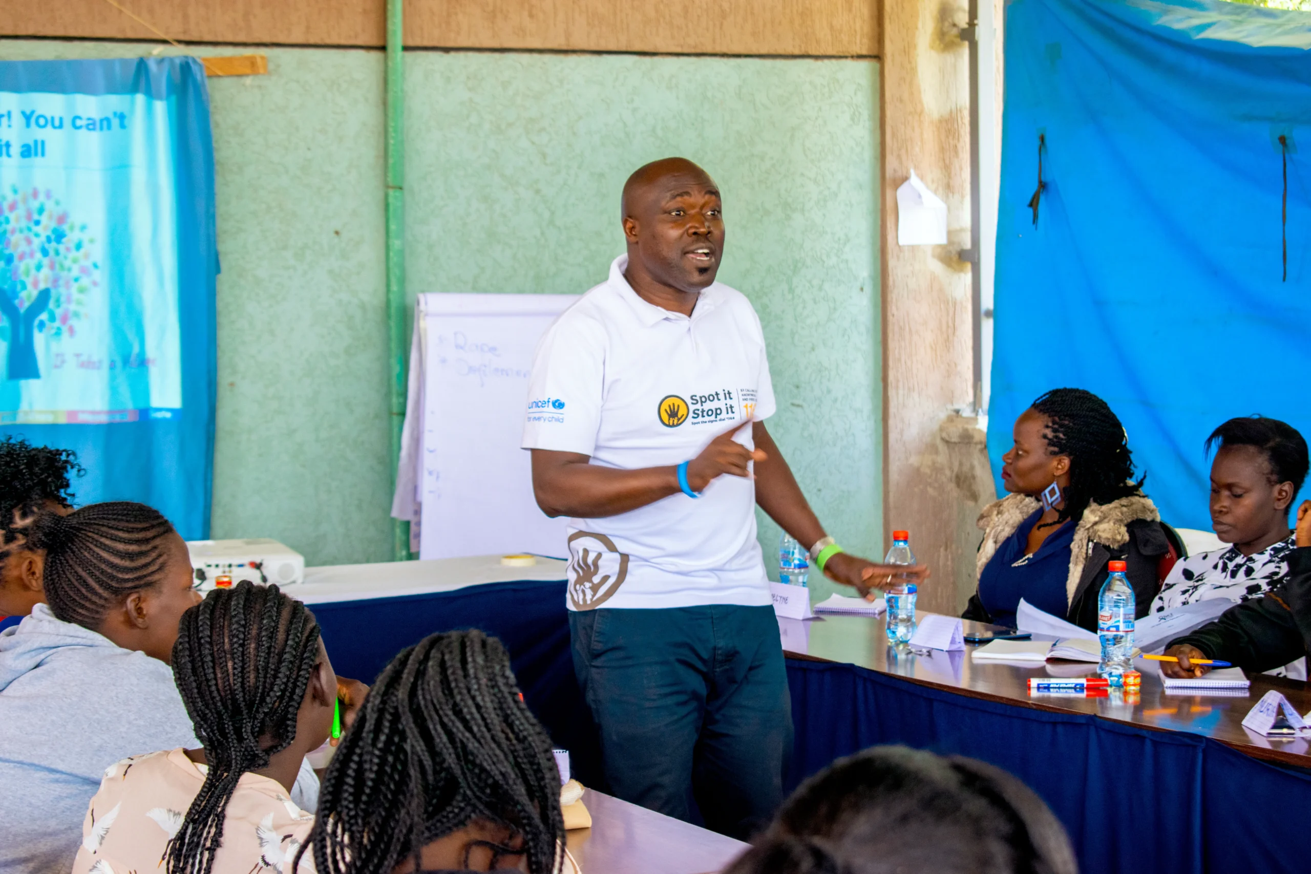 A man stands confidently addressing a group of engaged women in a classroom setting, emphasizing an interactive learning atmosphere.
